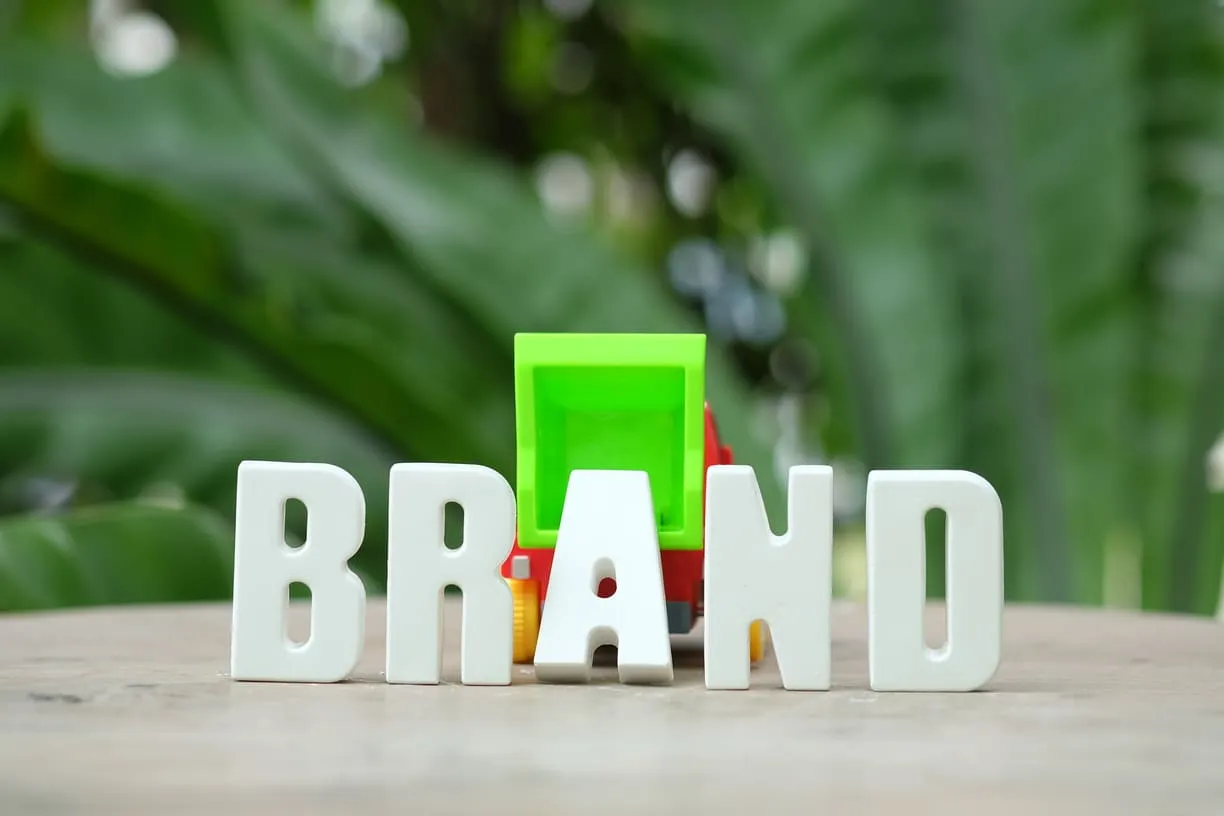 Hands arranging white letters spelling BRAND